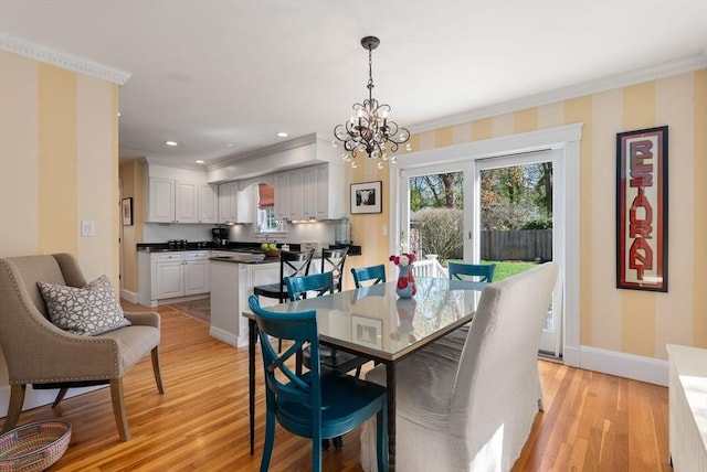 dining room with baseboards, ornamental molding, light wood-style flooring, and a notable chandelier