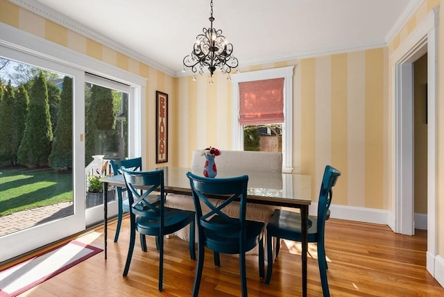 dining area with an inviting chandelier, baseboards, wallpapered walls, wood finished floors, and ornamental molding