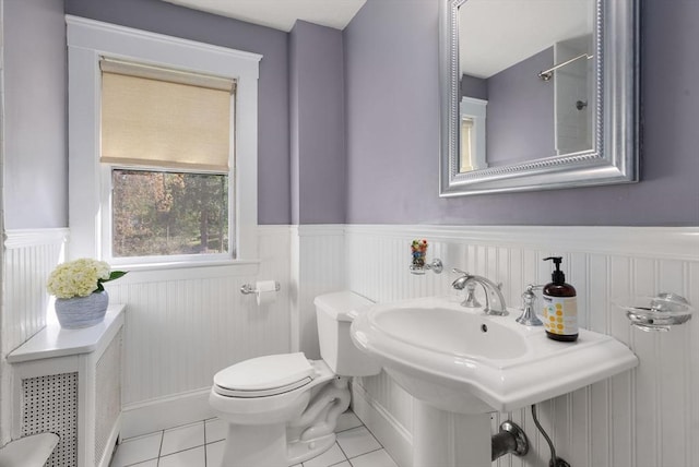 bathroom featuring a sink, wainscoting, tile patterned floors, and toilet