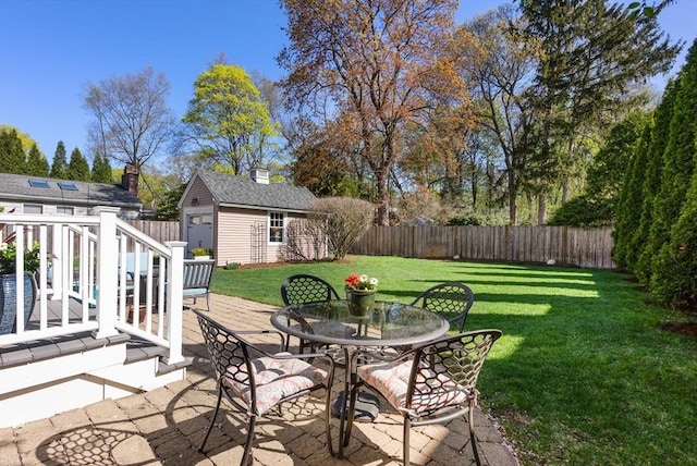 view of patio / terrace with an outdoor structure, a fenced backyard, a wooden deck, and outdoor dining space