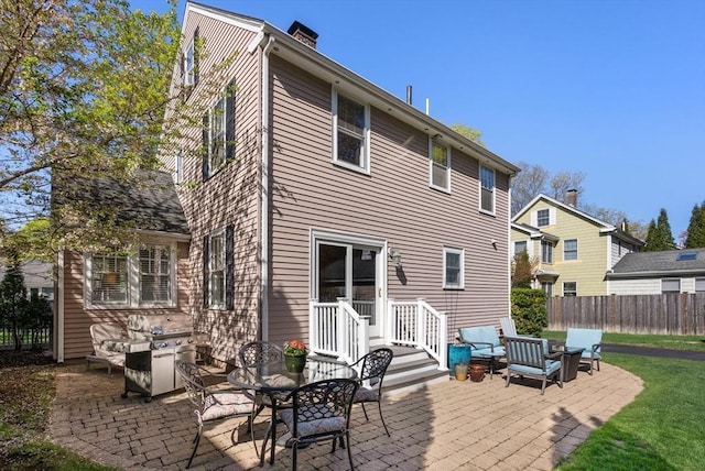rear view of house featuring a patio, fence, and a chimney