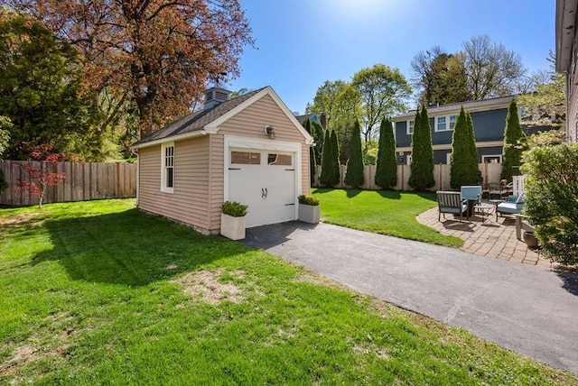 detached garage featuring aphalt driveway and fence