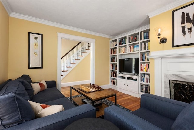 living room featuring ornamental molding, stairs, wood finished floors, a fireplace, and baseboards