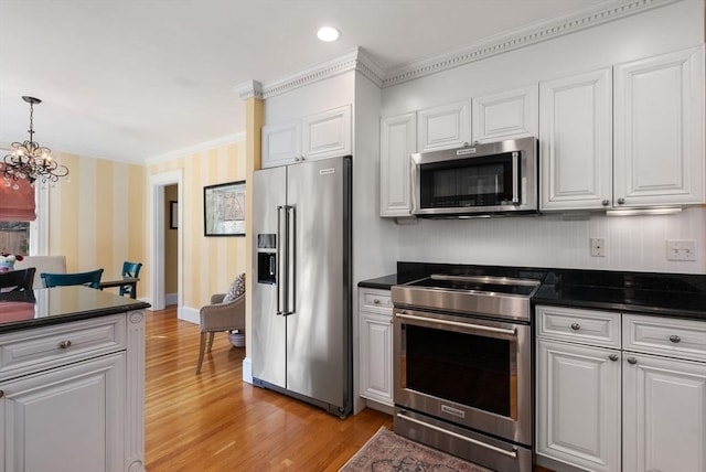 kitchen with dark countertops, an inviting chandelier, light wood-style floors, stainless steel appliances, and wallpapered walls