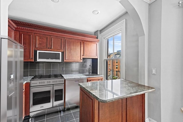 681 Massachusetts Ave Unit D, Boston, MA 02118 - kitchen with premium appliances, decorative backsplash, a sink, arched walkways, and light stone countertops