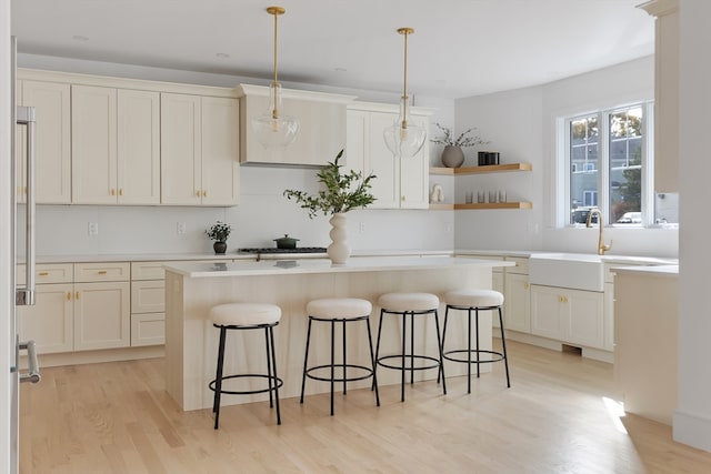 kitchen featuring light hardwood / wood-style floors, a breakfast bar area, decorative light fixtures, and a kitchen island