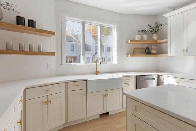 kitchen with light stone countertops, stainless steel dishwasher, sink, and light wood-type flooring