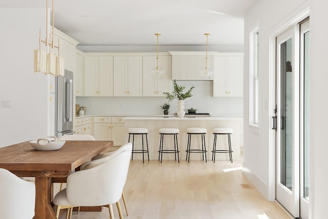 kitchen with high end refrigerator, pendant lighting, light wood-type flooring, and plenty of natural light