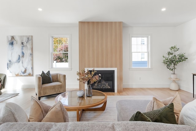 living room with a wealth of natural light, a large fireplace, and light wood-type flooring