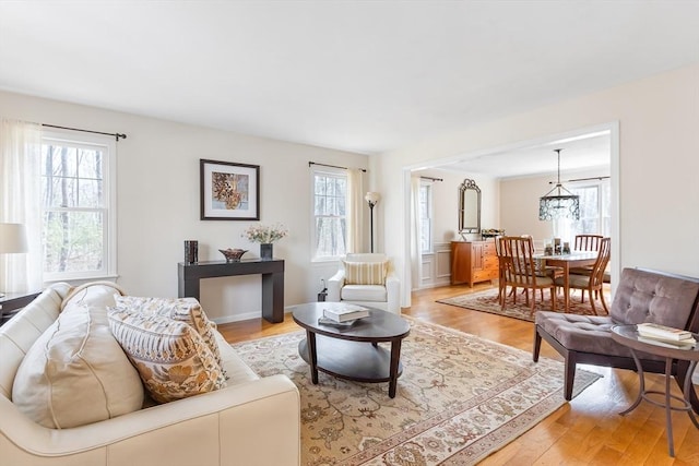 living area featuring light wood-style floors, a healthy amount of sunlight, and a chandelier