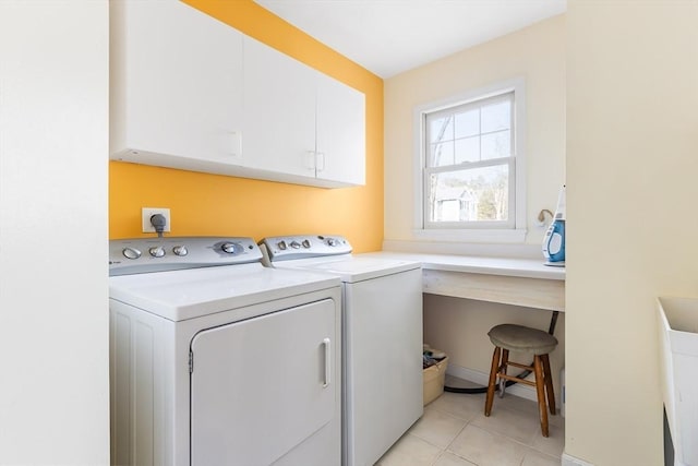 laundry area with washing machine and clothes dryer, light tile patterned floors, and cabinet space