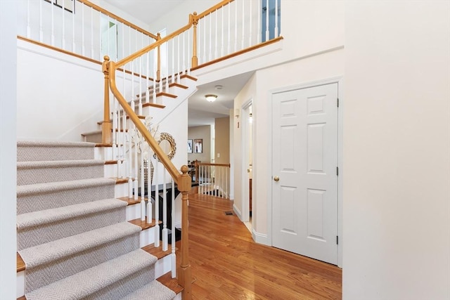 interior space with baseboards, wood finished floors, and a towering ceiling