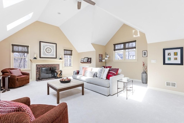 carpeted living room featuring a ceiling fan, visible vents, baseboards, a fireplace, and vaulted ceiling