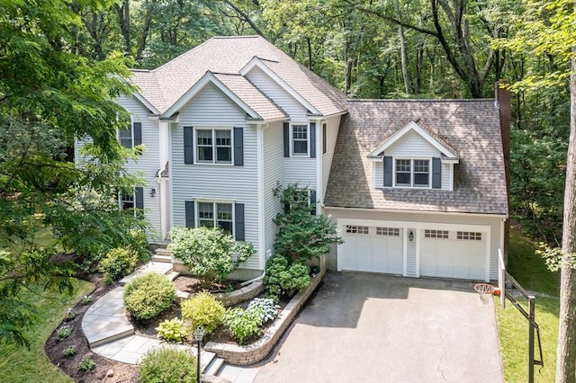 view of front facade featuring aphalt driveway, a garage, a chimney, and roof with shingles