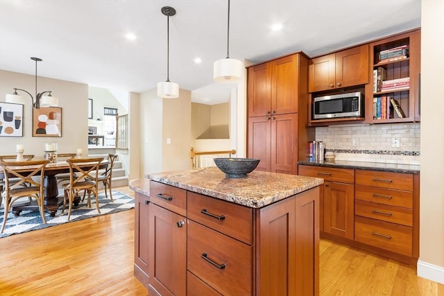 kitchen with stainless steel microwave, light wood-style floors, and brown cabinets