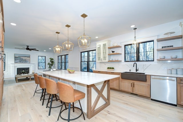 kitchen featuring a kitchen breakfast bar, stainless steel dishwasher, sink, light hardwood / wood-style flooring, and a kitchen island