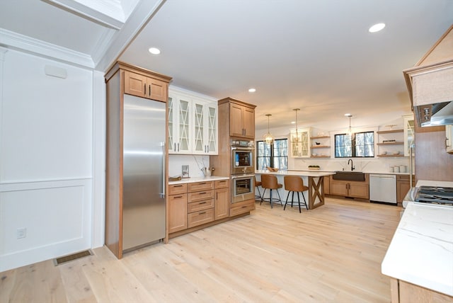 kitchen with a kitchen bar, light hardwood / wood-style flooring, hanging light fixtures, and appliances with stainless steel finishes