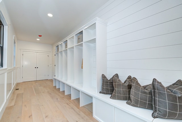 mudroom featuring light wood-type flooring and wood walls