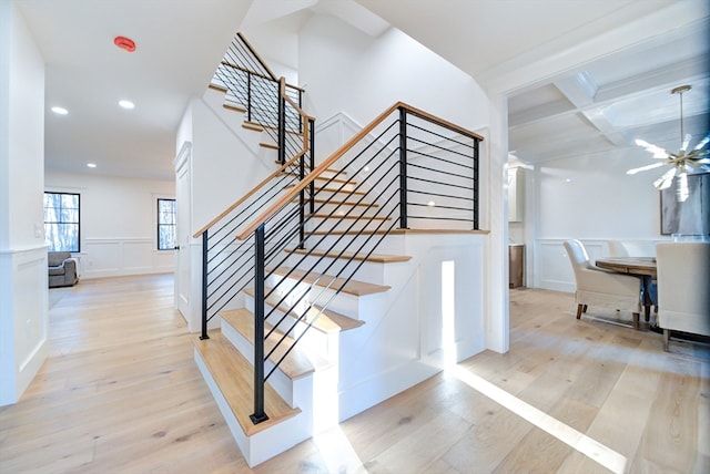 staircase featuring beamed ceiling, hardwood / wood-style flooring, and coffered ceiling