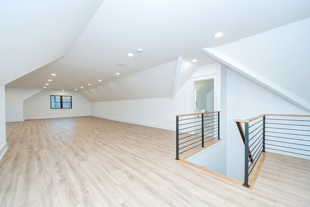 additional living space with light hardwood / wood-style floors and lofted ceiling