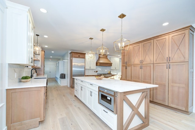 kitchen featuring backsplash, sink, pendant lighting, light hardwood / wood-style floors, and white cabinetry