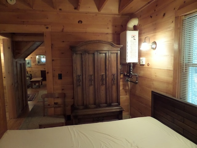 bedroom with wooden walls, water heater, and multiple windows