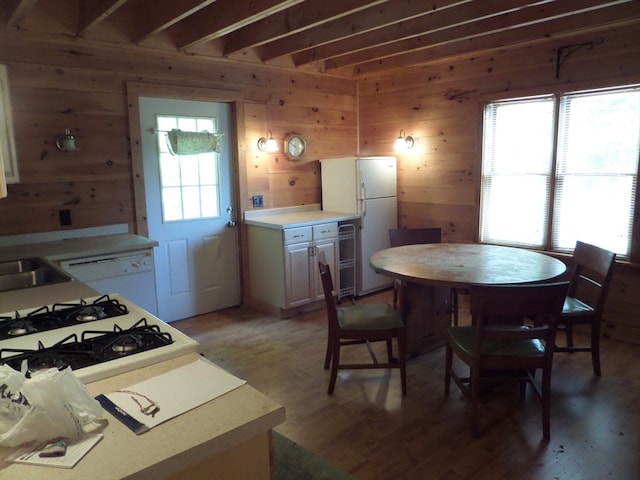 dining area with wine cooler, sink, wooden walls, and light hardwood / wood-style floors