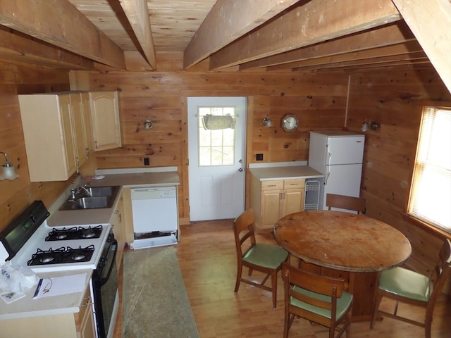 kitchen with lofted ceiling with beams, light hardwood / wood-style floors, sink, wood walls, and white appliances