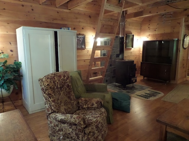 living room with wood walls, a wood stove, and hardwood / wood-style flooring