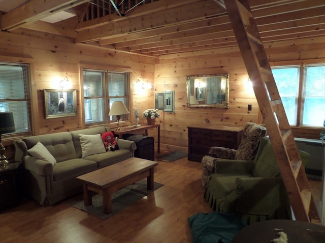 living room with wood-type flooring, wood walls, electric panel, and beamed ceiling