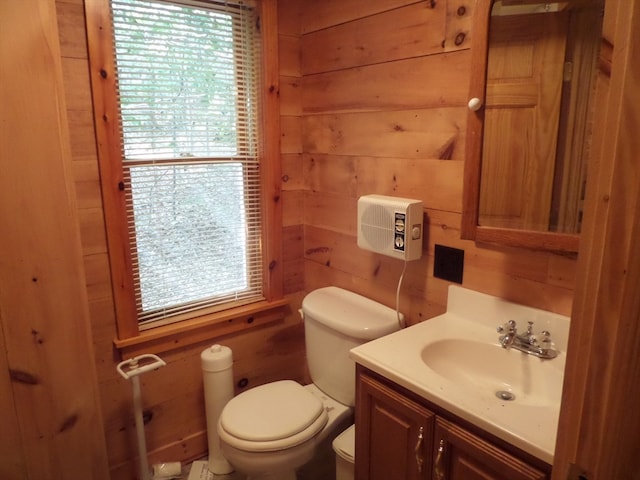 bathroom with vanity, wood walls, toilet, and a wealth of natural light