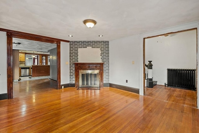 18 Newhall St, Malden, MA 02148 - unfurnished living room featuring radiator heating unit, a fireplace, and wood finished floors
