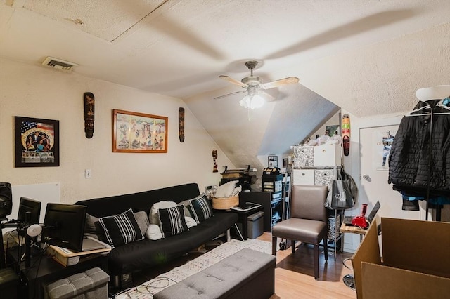 living area featuring wood finished floors, ceiling fan, lofted ceiling, and a textured ceiling