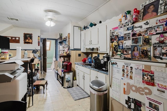 kitchen with freestanding refrigerator, white cabinets, dark countertops, vaulted ceiling, and a sink