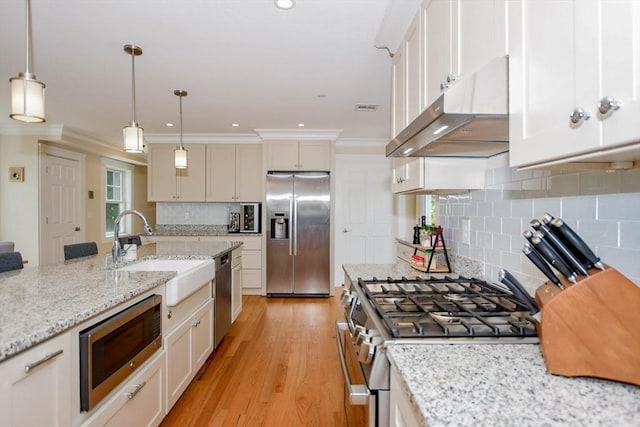 324 Front St Unit 4, Marion, MA 02738 - kitchen with appliances with stainless steel finishes, under cabinet range hood, ornamental molding, decorative backsplash, and light wood finished floors