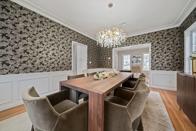 dining area featuring a notable chandelier, ornamental molding, and light hardwood / wood-style floors