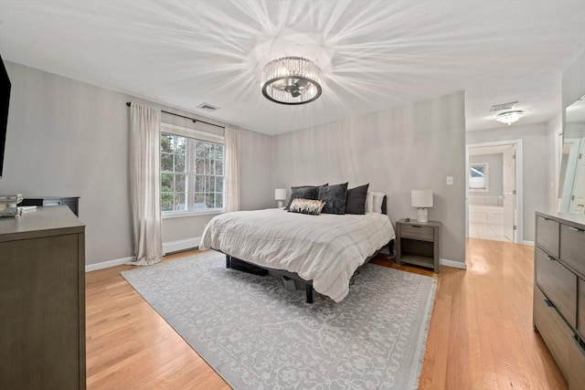 bedroom with a notable chandelier and light wood-type flooring