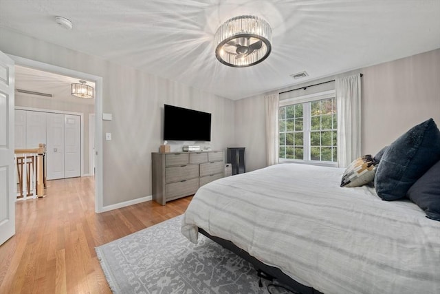 bedroom with light wood-type flooring and a notable chandelier