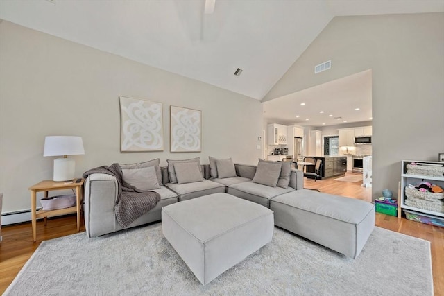 living room featuring high vaulted ceiling and light hardwood / wood-style flooring