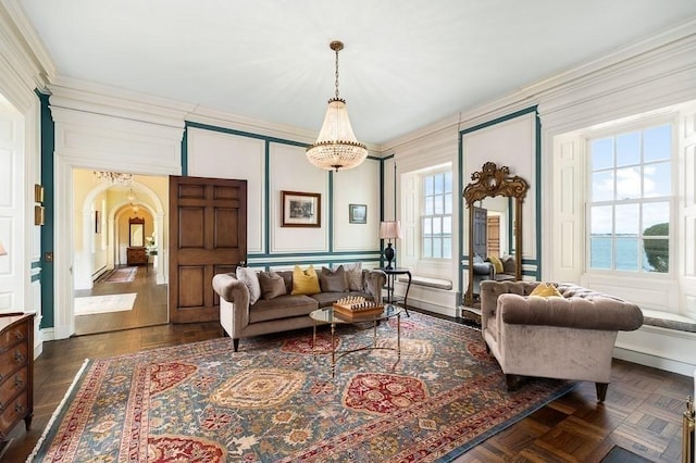 living area with crown molding, arched walkways, and a decorative wall