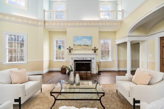 living room with a premium fireplace, a high ceiling, decorative columns, and baseboards