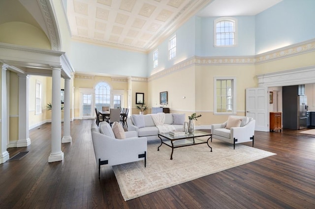 living area with baseboards, decorative columns, a towering ceiling, and dark wood finished floors