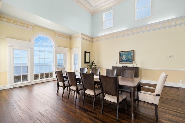 dining area featuring baseboards, ornamental molding, dark wood-style floors, and a towering ceiling