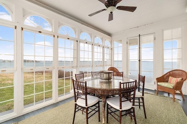 sunroom / solarium featuring a water view, ornamental molding, and wood finished floors