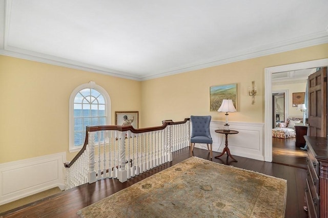 bedroom with crown molding, a wainscoted wall, a decorative wall, and dark wood-style flooring