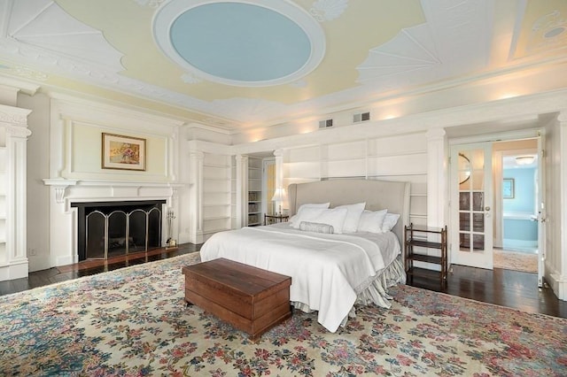 bedroom featuring visible vents, ornamental molding, wood finished floors, and a fireplace