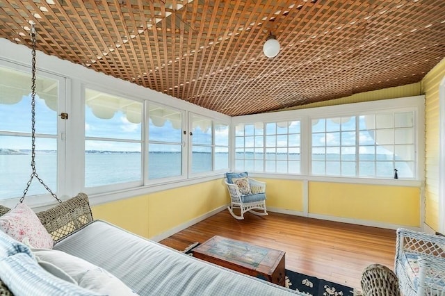 sunroom / solarium featuring baseboards, a water view, and hardwood / wood-style floors