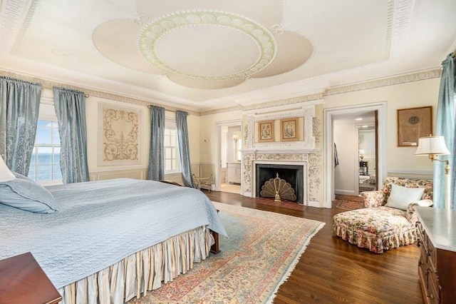 bedroom with ornamental molding, dark wood finished floors, wainscoting, and a fireplace