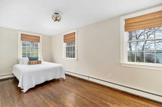 bedroom featuring a baseboard heating unit and dark wood-style floors
