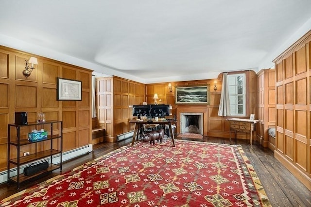 home office with a brick fireplace, dark wood-style flooring, and a baseboard radiator
